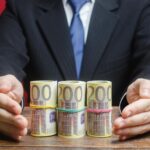 Przedsiębiorca pokrywa rękami pieniądze euro gest ochrony zapewnienie pieniędzy kredyt