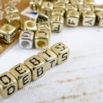 Zbliżenie tekstu długu wykonanego ze złotych bloków zabawek na stole