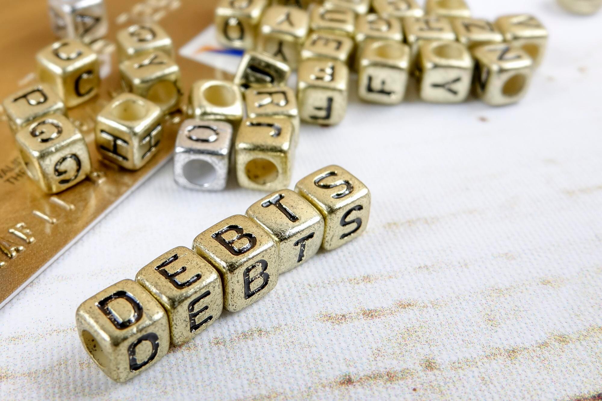 Zbliżenie tekstu długu wykonanego ze złotych bloków zabawek na stole