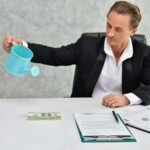 Biznesmen nawadniający papierową walutę w biurze