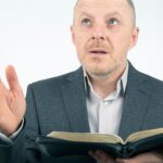 Mężczyzna w garniturze czyta Biblię.