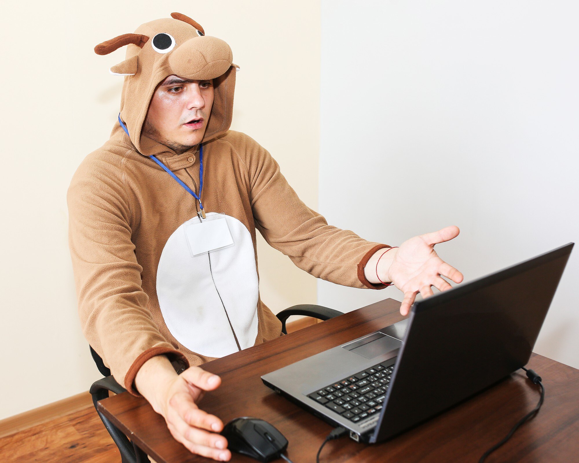 Pracownik biurowy w stroju cosplay krowy. Facet w zabawnej piżamie zwierzęcej w pobliżu laptopa. Parodia menedżera.