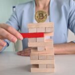 Kobieta grająca w Jenga z Bitcoinem na szczycie wieży
