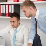 Szczęśliwi młodzi biznesmeni pracują w nowoczesnym biurze na komputerze