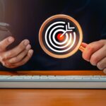 Cel czerwony bullseye ikona dartboard wewnątrz szkła powiększającego w ręku biznesmena, który używa inteligentnego telefonu komórkowego Digital marketing biznes wyszukiwanie online znaleźć trend z online koncepcji mediów społecznościowych