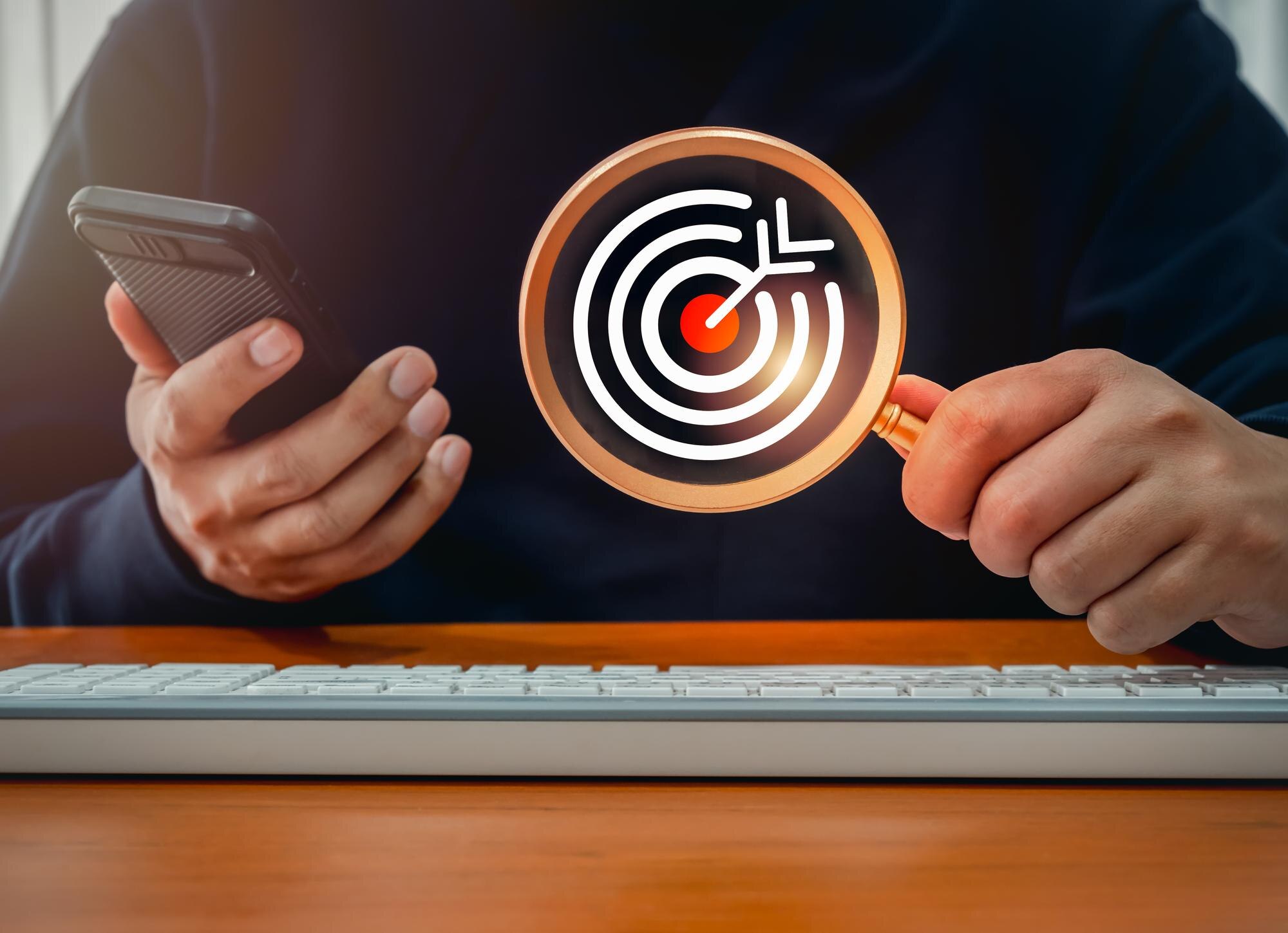Cel czerwony bullseye ikona dartboard wewnątrz szkła powiększającego w ręku biznesmena, który używa inteligentnego telefonu komórkowego Digital marketing biznes wyszukiwanie online znaleźć trend z online koncepcji mediów społecznościowych