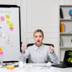 Marketingowa inteligentna śliczna biznesowa dama w pasiastej koszuli w biurze zły trzymający pięści