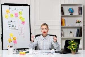 Marketingowa inteligentna śliczna biznesowa dama w pasiastej koszuli w biurze zły trzymający pięści