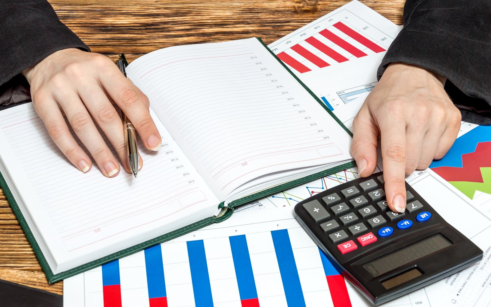Biznes kobieta liczy na kalkulatorze i zapisuje informacje finansowe w notatniku Koncepcja biznesowa