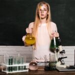 Śmieszne małe dziecko w wieku szkolnym robi eksperymenty w wybuchu laboratoryjnym w laboratorium mała dziewczynka scien