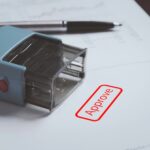 Zbliżenie stempla z czerwonym tekstem zatwierdzającym na papierze w celu zatwierdzenia zezwolenia na projekt biznesowy dokumentu i koncepcji certyfikatu ISO
