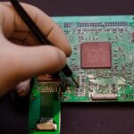 Naprawa telefonów komórkowych i różnych gadżetów elektronicznych Chip z urządzenia elektronicznego leży na stole na czarnym tle
