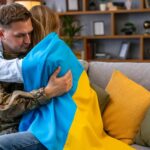 Para siedzi na kanapie i obejmuje Żołnierza w mundurze jest w domu z żoną Flaga Ukrainy