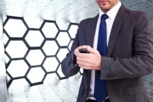 Skoncentrowany biznesmen wysyłający SMS-y na swoim telefonie komórkowym przeciwko sześciokątnemu pokojowi
