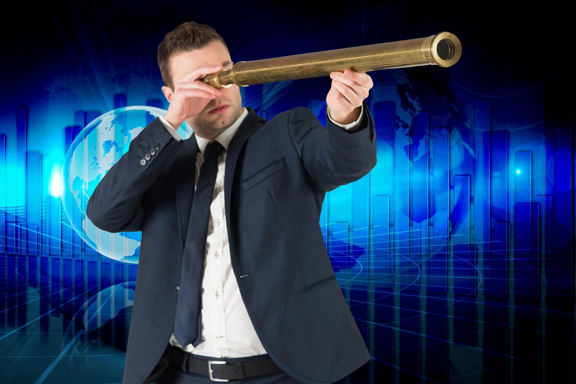 Biznesmen patrzeje przez teleskop przeciw globalnej biznesowej grafice w błękicie
