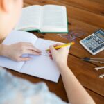 szkoła, edukacja, ludzie i koncepcja uczenia się - zbliżenie dłoni ucznia lub kobiety z linią rysowania linijką i ołówkiem w zeszycie
