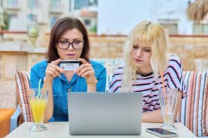 Matka i nastoletnia córka robią razem zakupy online za pomocą laptopa
