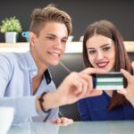 Młoda uśmiechnięta para trzymająca kartę kredytową