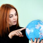 Portret szczęśliwa młoda kobieta trzyma geograficzną kulę ziemską świat w ona ręki