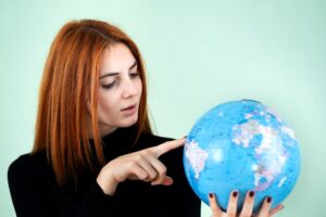 Portret szczęśliwa młoda kobieta trzyma geograficzną kulę ziemską świat w ona ręki